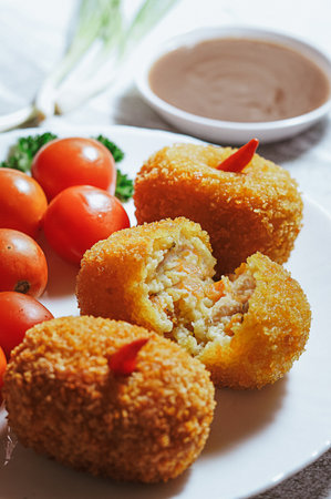 delicious croquette snack food with tomatoes and vegetables on a plate with chili sauce on a marble table (2)の写真素材
