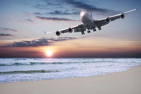 Jet liner is flying over the beach at sunsetの写真素材