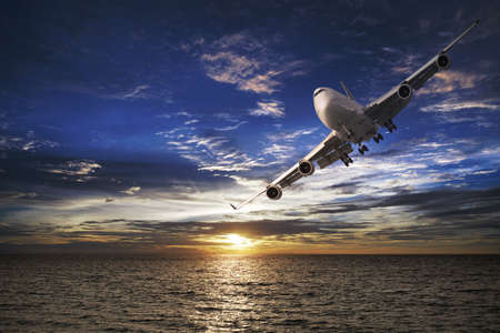 Jet plane over the sea at sunset timeの写真素材