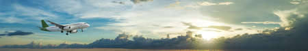 Jet plane is maneuvering for landing in a spectacular sunset sky. Panoramic composition.