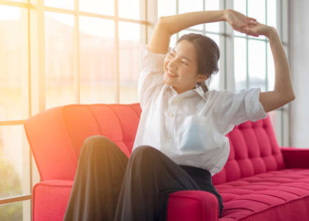 Attractive Asian women work from home on red sofa with laptop in her Living room.