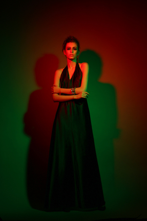 Model posing in black classic dress. Green and red. Studio shootの写真素材