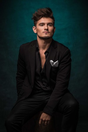 Beautiful athletic bodybuilder male model posing in studio. Expression on camera. Brutal man in leather suit.の写真素材