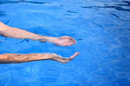 Two human hands taking water on a blue backgroundの写真素材