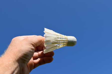 Man hand hold a badminton ball against the skyの写真素材