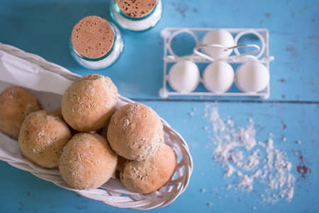 Fresh homemade buns on a basket with eggs and jar of salt.の写真素材