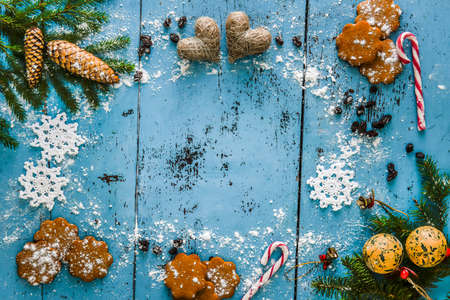 Christmas background with snowflake, gingerbread, candy cane, hearts and fir tree decoration. Old blue wooden table.の写真素材