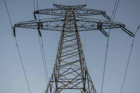 big electric power tower at sunset with a yellow moon in the background