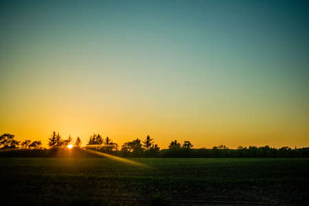 water pump at sunset in a big green field Europeの写真素材