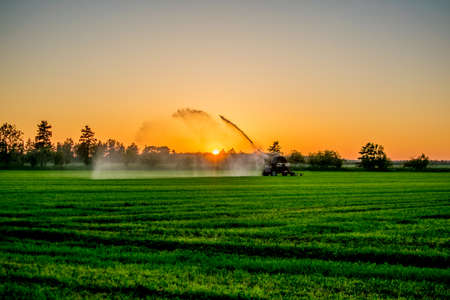 water pump at sunset in a big green field Europeの写真素材