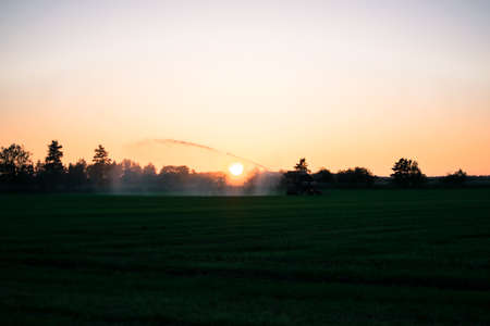 water pump at sunset in a big green field Europeの写真素材