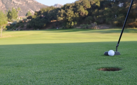 Putting the golf ball to the hole on a putting green of the golf courseの写真素材