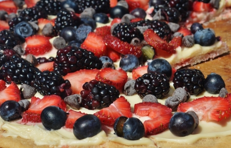 A colorful fruit pizza with blueberries, blackberries, strawberries, and chocolate chips の写真素材
