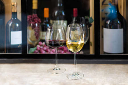 Red and white wine glasses with wine bottle backgroundの写真素材