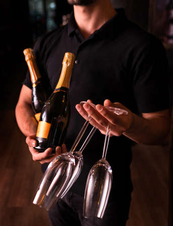 Man holding Champagne and glasses on dark backgroundの写真素材