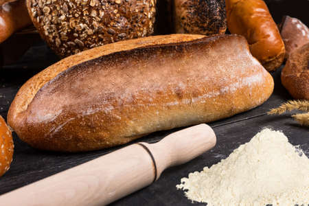 Fresh loaves of bread with flour wheat and gluten on a dark backgroundの写真素材