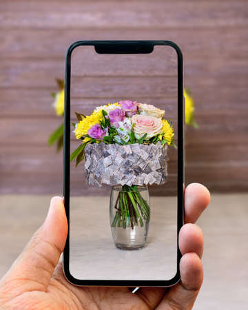 Taking photo of flower bouquet in the vase with mobile phoneの写真素材