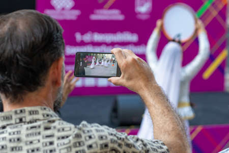 Man recording video of a Azerbaijani national dancer with smartphone