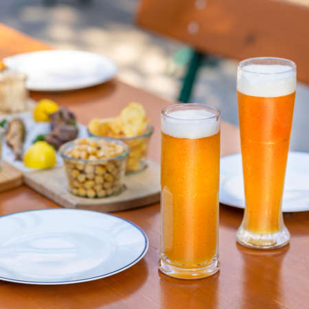 Beer mugs, glasses with snacks on the tableの写真素材