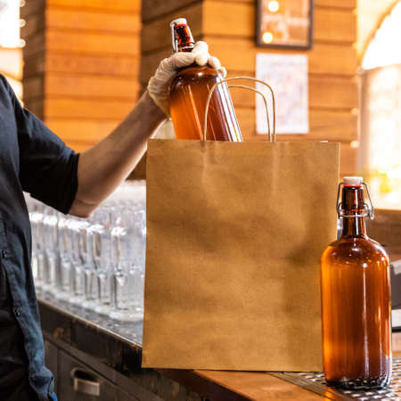 Restaurant worker putting beer bottle to shopping bagの写真素材