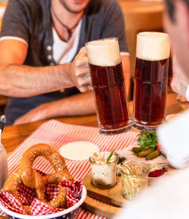 Clinking dark, black beer mugs close up, snacks on the tableの写真素材