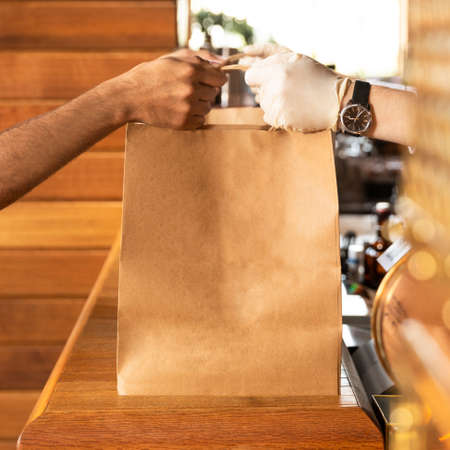 Worker giving a ready food order bag to the clientの写真素材