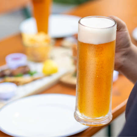 Man holding beer mug with snacks on the table