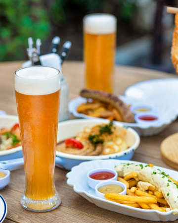 Beer mugs with sausage, meat meal, pretzel, sauce on the tableの写真素材