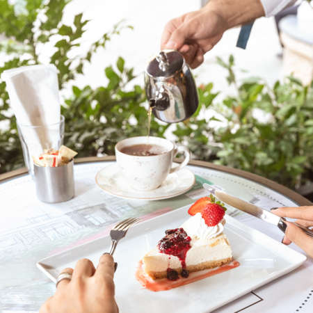 Waiter pouring tea, woman cutting dessertの写真素材