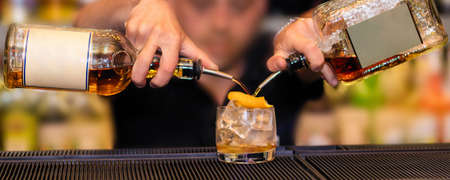 Barman making a new alcoholic cocktail, pouring drinks into a glass
