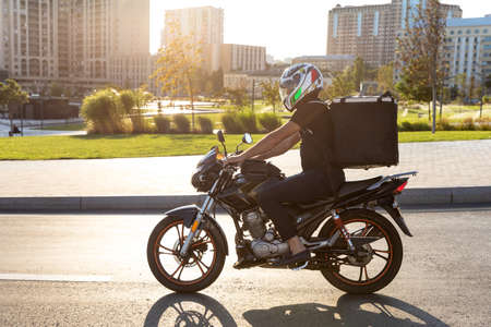 Courier worker driving a motorcycle at the sunsetのeditorial素材