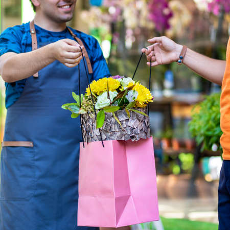 Flower shop worker, florist giving a flower boutique to the clientの写真素材