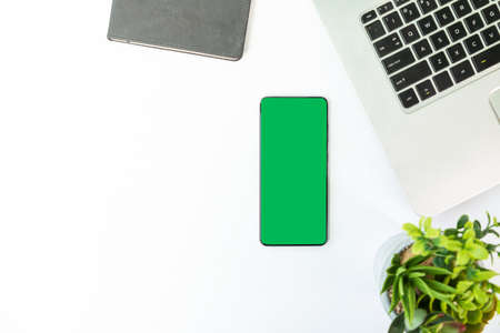 Green screen smartphone on the desk with laptop top viewの写真素材