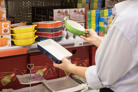 Woman holding a colorful kitchen plates at the storeの写真素材