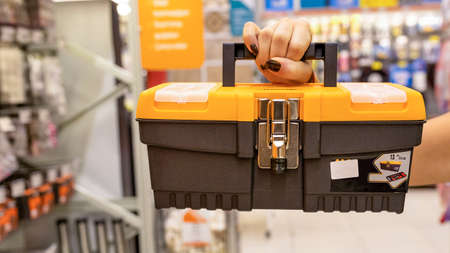Woman holding orange heavy duty plastic tool box at the storeの写真素材