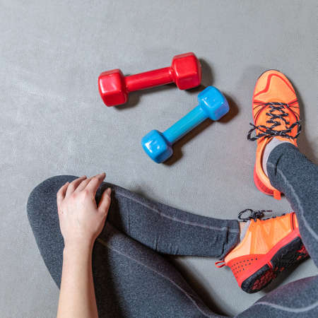Fitness woman legs with colorful dumbbells top viewの写真素材