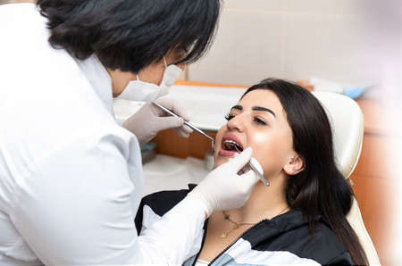 Young caucasian woman sitting in dental chair at medical center while professional doctor fixing her teethの写真素材
