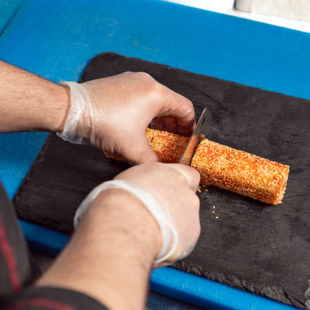 Chef cutting the Kani sushi hot roll close up