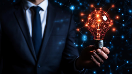 Businessman is holding a lightbulb with a network of connections, symbolizing innovation and technological advancementの素材