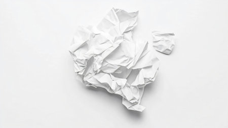 Crumpled piece of white paper is lying on a white background, creating a high-key minimalist compositionの素材