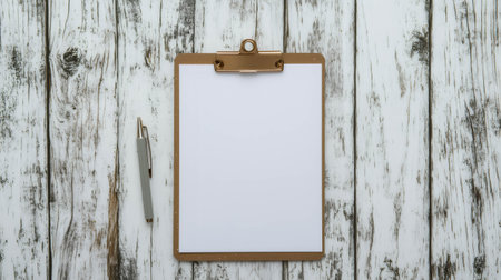 White blank paper on wooden clipboard with a pen on white wooden desk, writing and planning conceptの素材