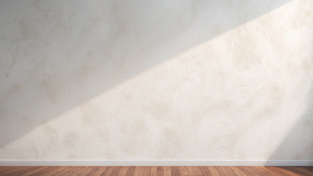 Soft afternoon light streams across a simple white wall and warm wooden floor, creating a calm and inviting atmosphere in a spacious interior.の素材