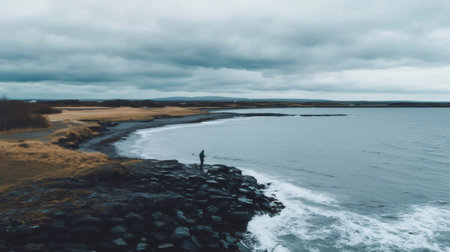 Lonely fisherman fishing on a rocky shore in Iceland, enjoying a peaceful moment surrounded by the beauty of natureの素材