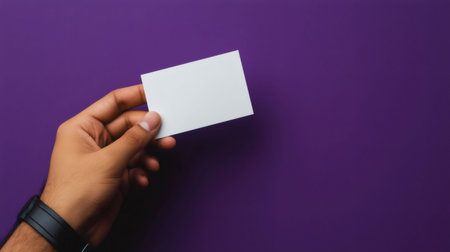 Man holding a white empty business card on a purple backgroundの素材