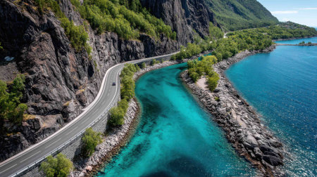 A winding road runs alongside bright turquoise water, surrounded by lush greenery and rocky cliffs. The picturesque landscape showcases natureâs beauty on a clear day.の素材