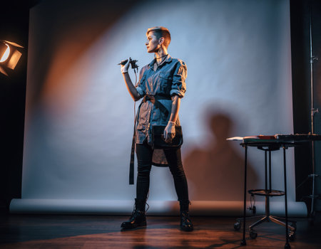 A model stands confidently in a creative studio, holding a camera as they prepare for a photo shoot. Bright lights create a dramatic atmosphere.の素材