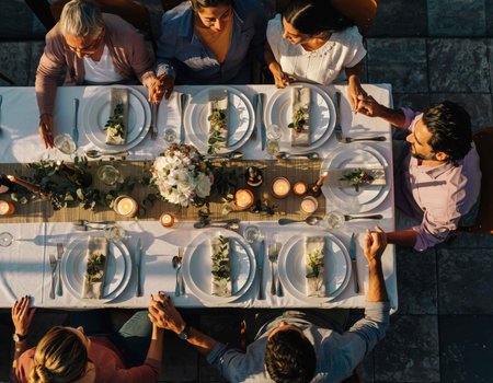 A group of friends enjoys a delightful dinner together, seated around a long table decorated with flowers and candles. The evening sky adds warmth to the atmosphere.の素材