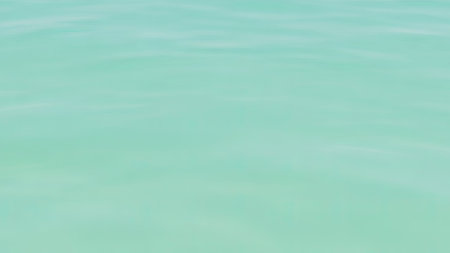 Calm, serene turquoise water surface with subtle ripples and soft light creating a peaceful, abstract backdropの素材