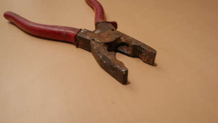 red pliers that have started to rust on the wooden table
