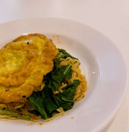 Fried noodles with fried egg on a wooden tableの写真素材